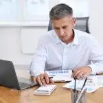 Small business owner reviewing VAT scheme summary and calculating flat rate tax